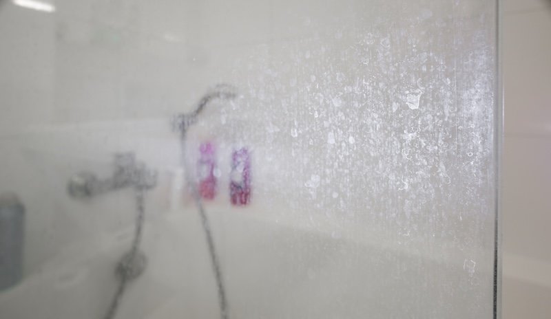 Dépôts de calcaire et de savon sur une paroi de douche vitrée